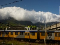 Uitzicht vanaf de trein op een Metorrail-trein en een bewolkte Tafelberg